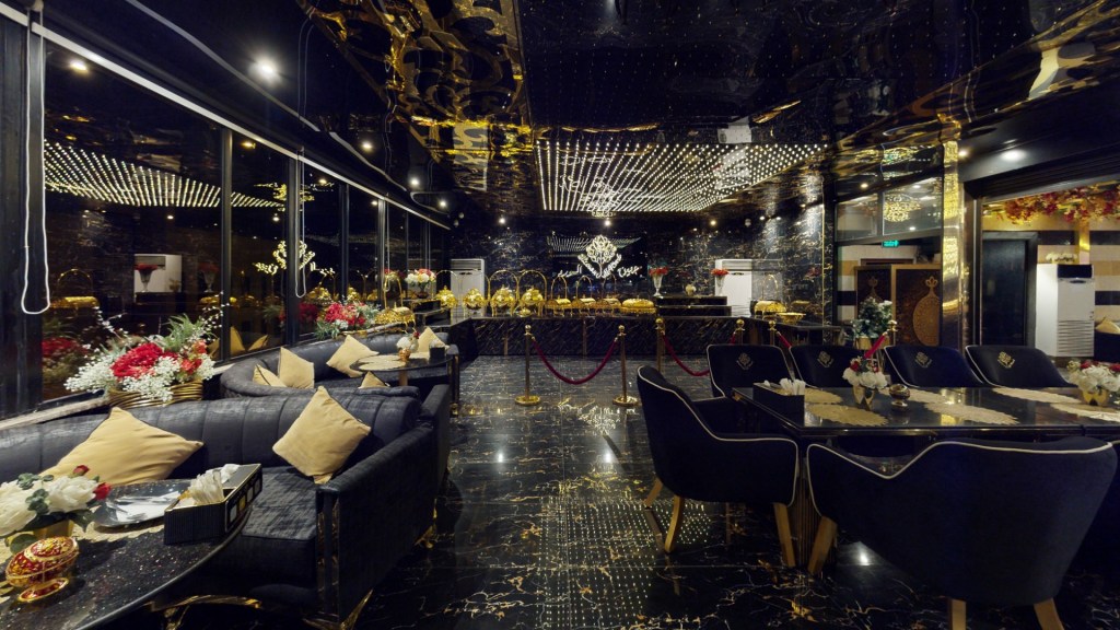An elegantly designed interior of a restaurant featuring black and gold decor, plush seating, and floral arrangements on tables.