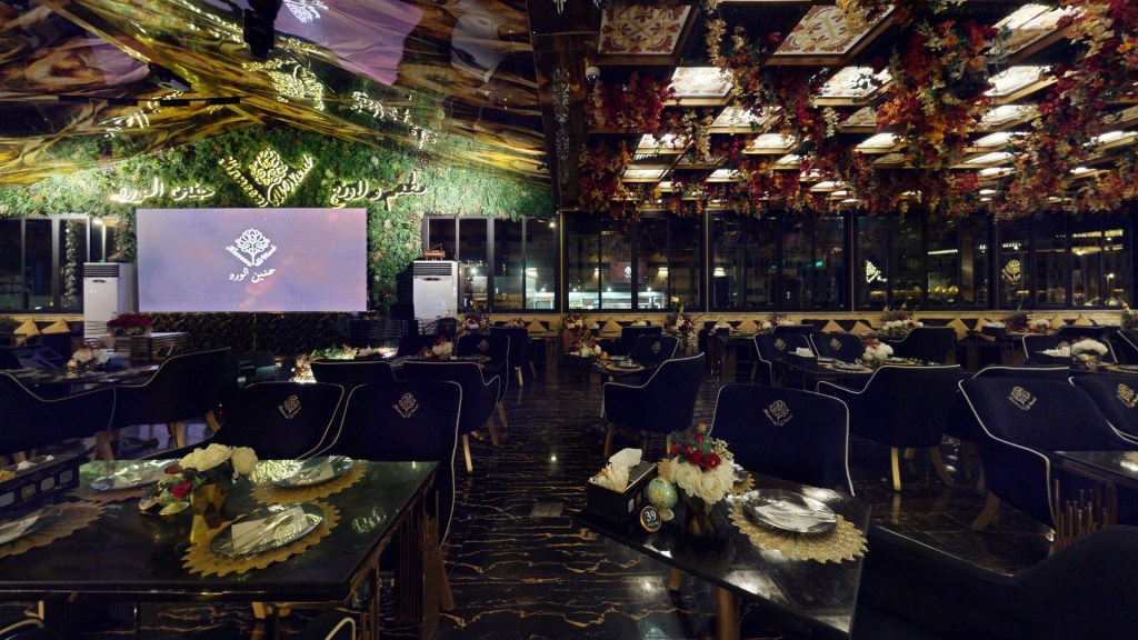 Elegant restaurant interior featuring mirrored ceiling, floral decorations, and luxurious seating arrangements.